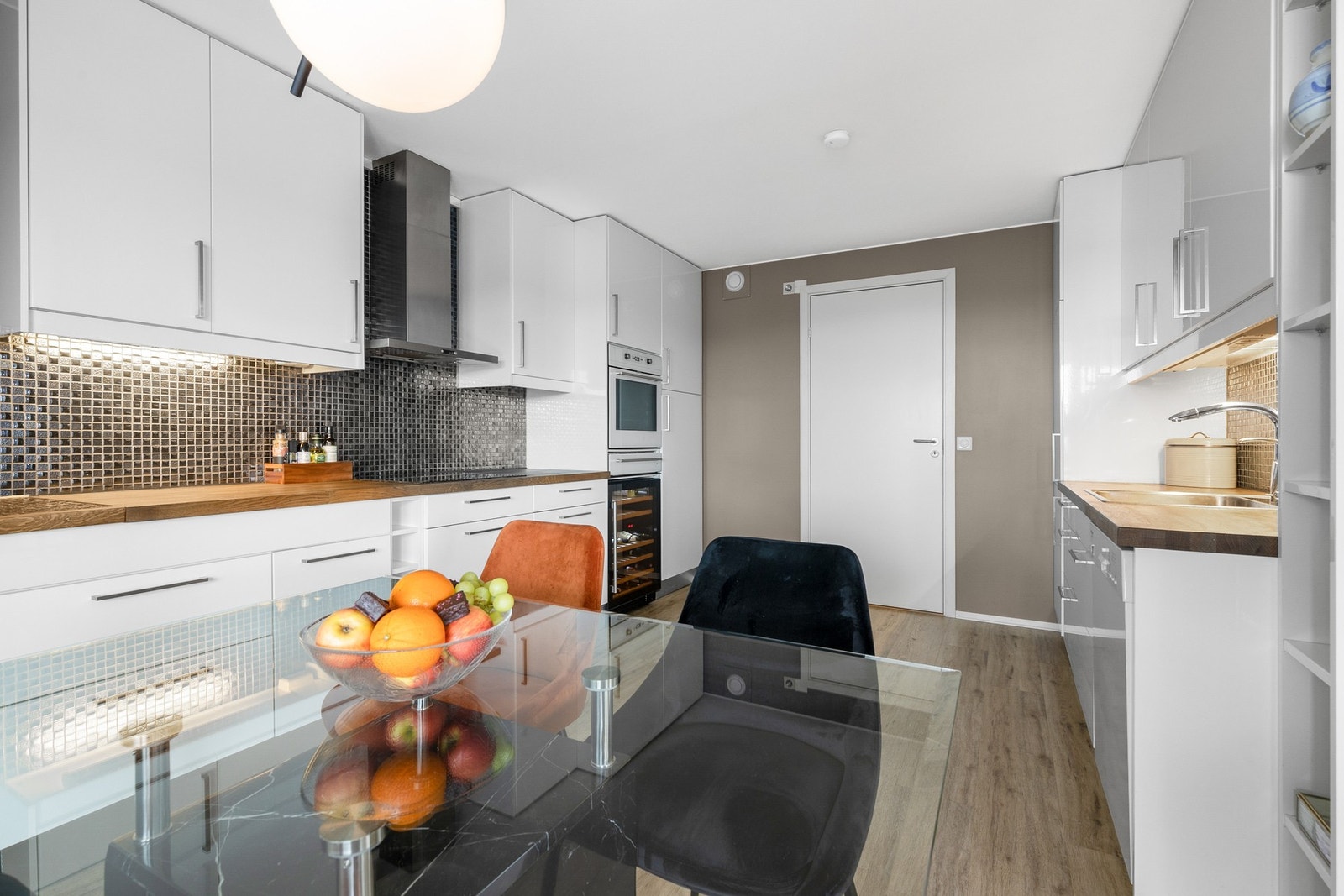 Innredningen har integrerte hvitevarer, herunder kjøl/fryseskap, oppvaskmaskin, platetopp, vinskap og stekeovn Galleribilde