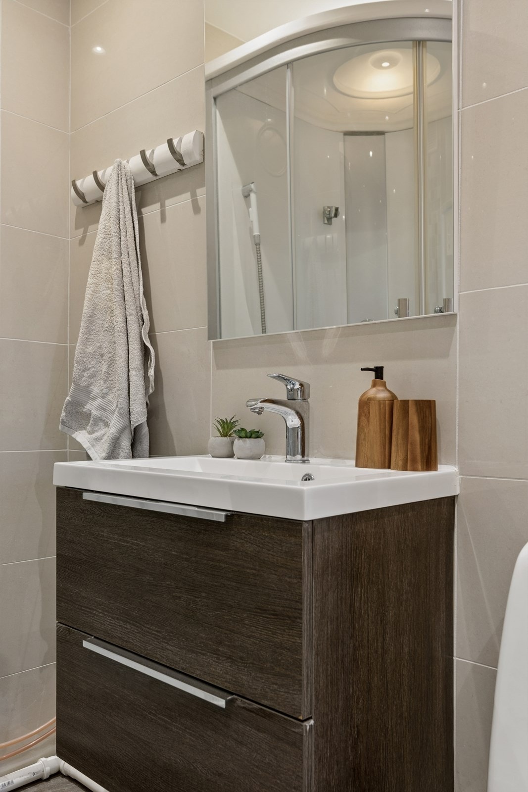 Innredningen består av servant med skuffer, speilskap og et praktisk høyskap for god oppbevaring. Galleribilde