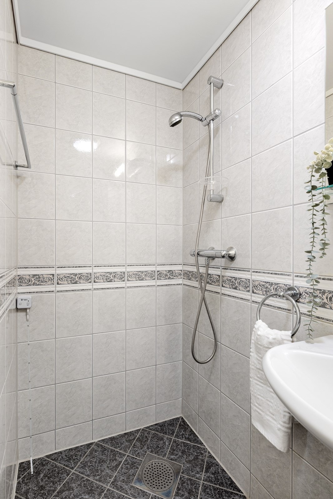 Badet er utstyrt med fliser på gulv og vegger, varmekabler i gulvet, samt dusj, toalett og servant. Galleribilde