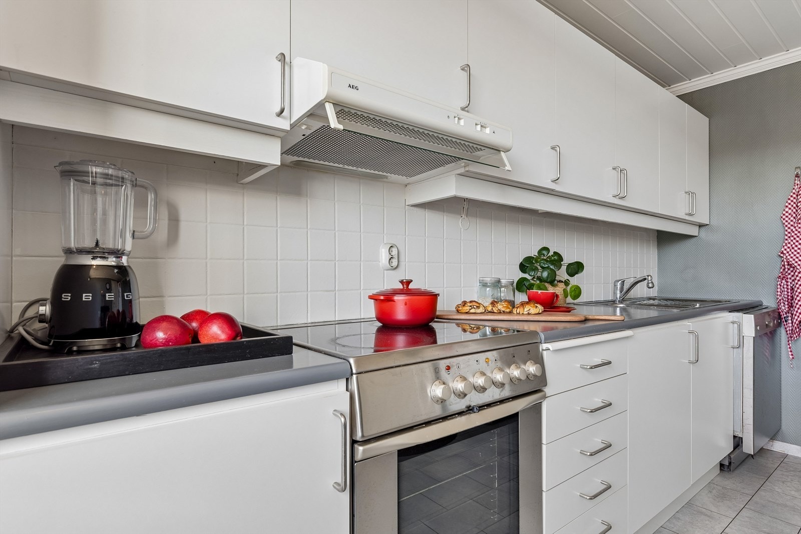 Laminatbenkeplaten har en nedfelt dobbel kum i rustfritt stål. Varmtvannsberederen er plassert i benkeskapet. Galleribilde