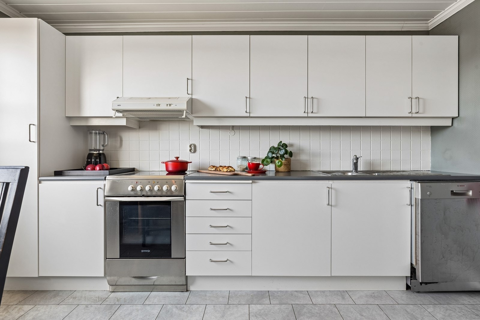 Kjøkkeninnredningen fra 2004 er funksjonell med slette, folierte fronter og flisfelt over benken. Galleribilde