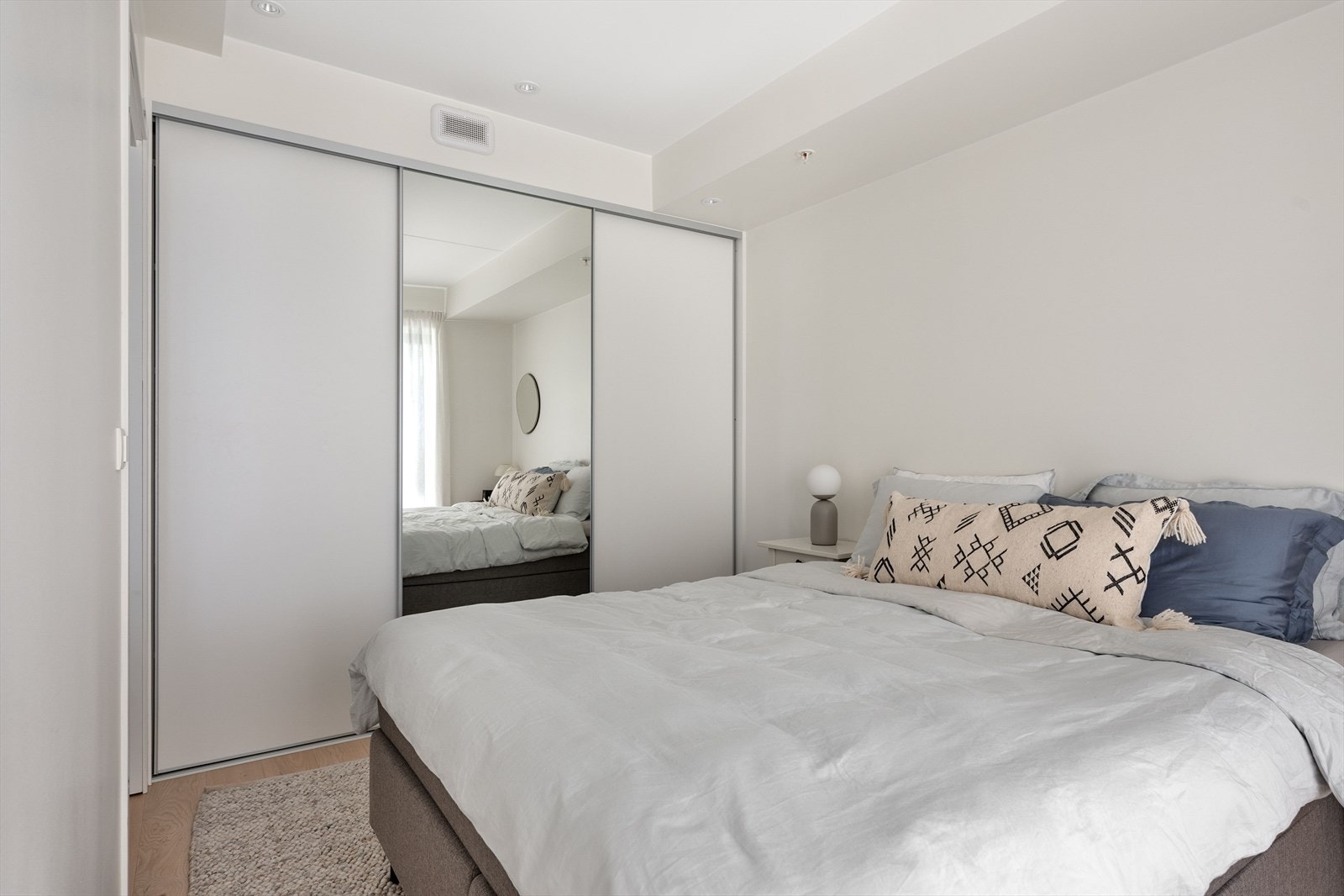 Plassrik skyvedørsgarderobe hvor en dør har speilglass. Det er downlights i himlingen. Galleribilde