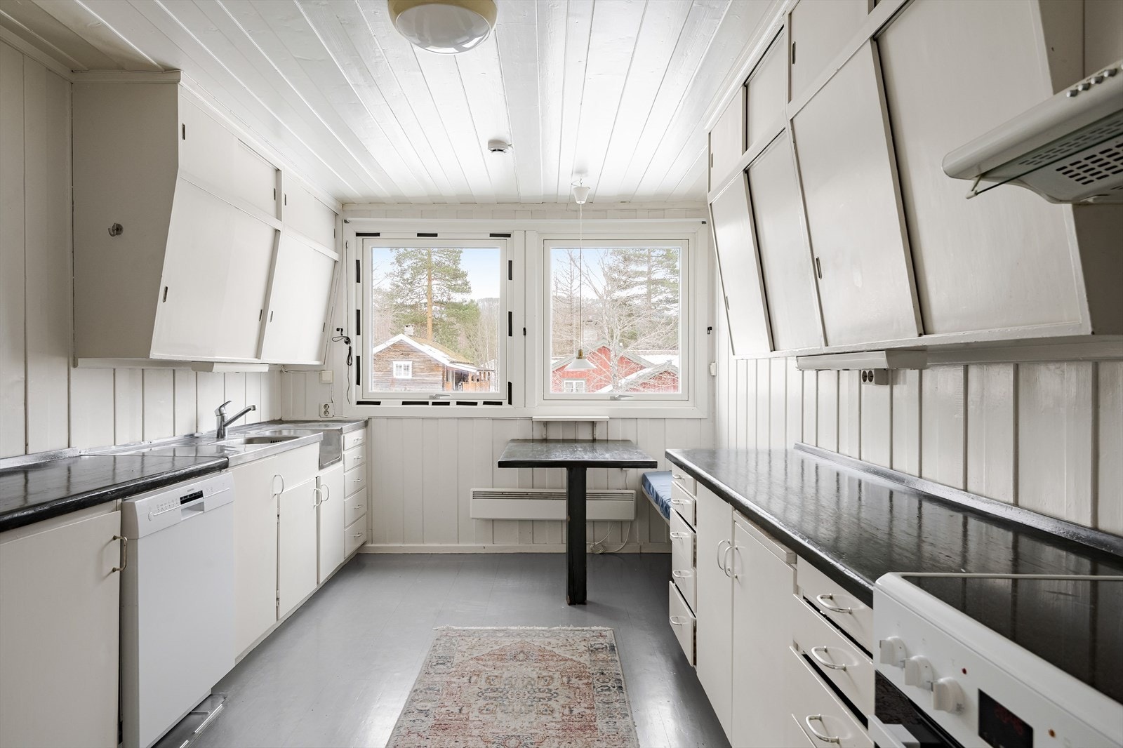 Kjøkkenet er utstyrt med eldre innredning med glatte malte fronter og heltre benkeplate. Det er opplegg for oppvaskmaskin og komfyr. Galleribilde