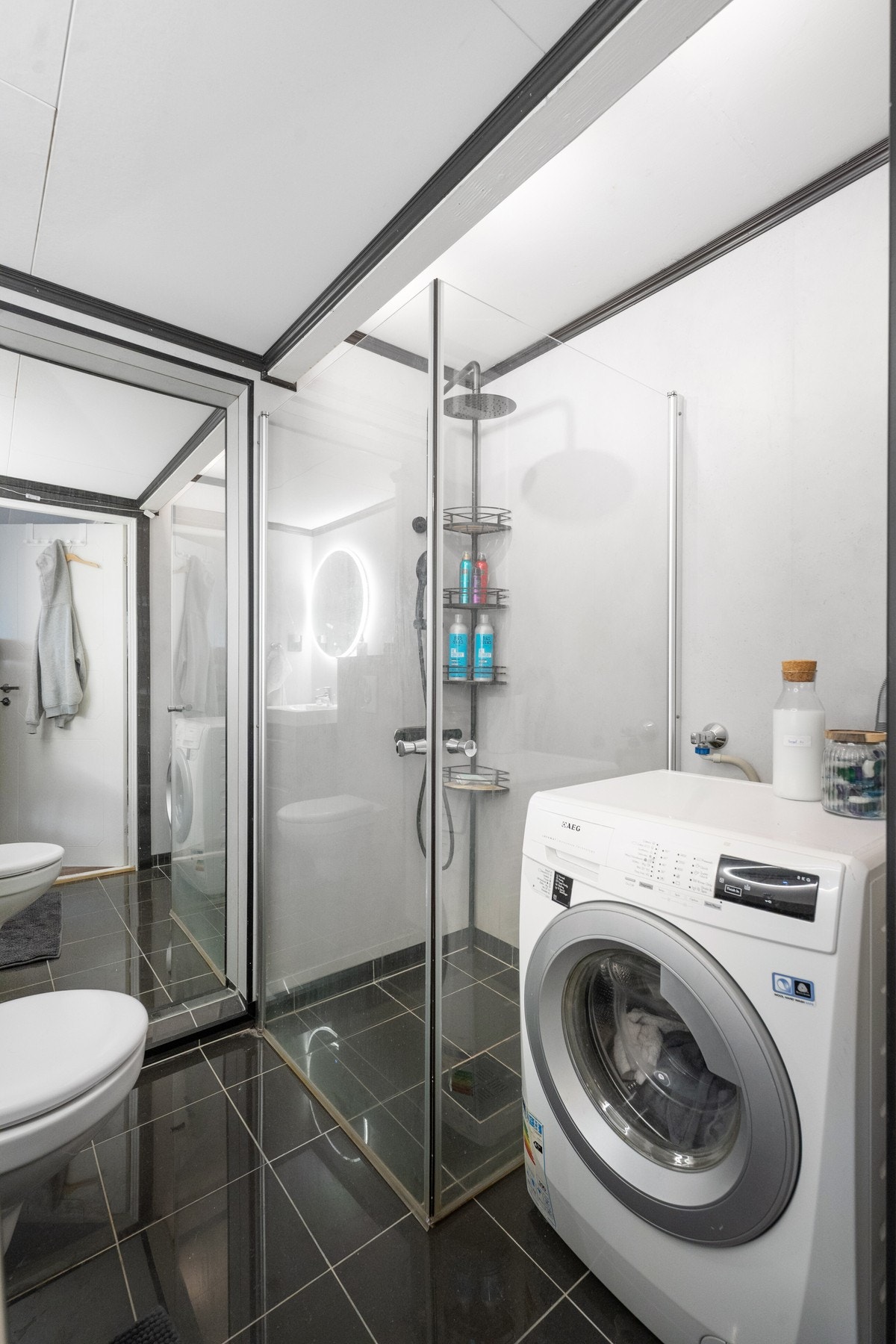 Badet har flislagt gulv med varmekabler, moderne innredning, dusjhjørne og opplegg for vaskemaskin. Galleribilde