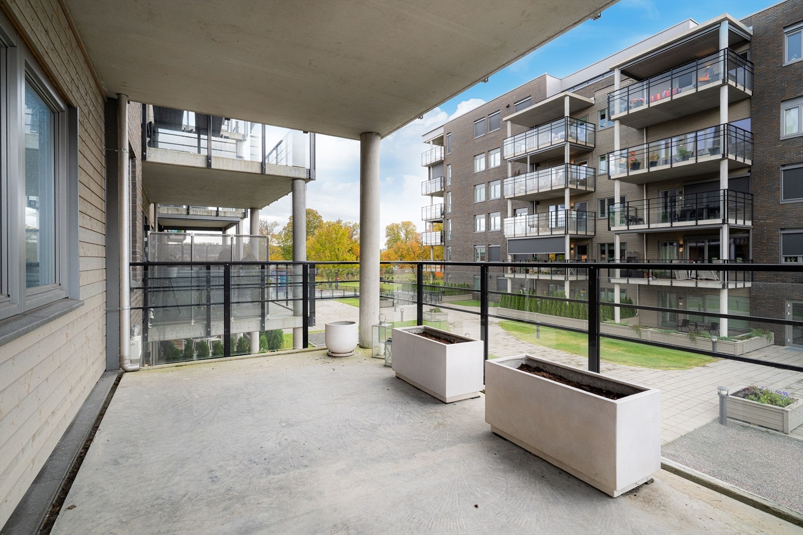 En skjermet og solrik balkong som vender ut mot borettslagets pene fellesareal - et perfekt sted for rolige kaffestunder. Galleribilde