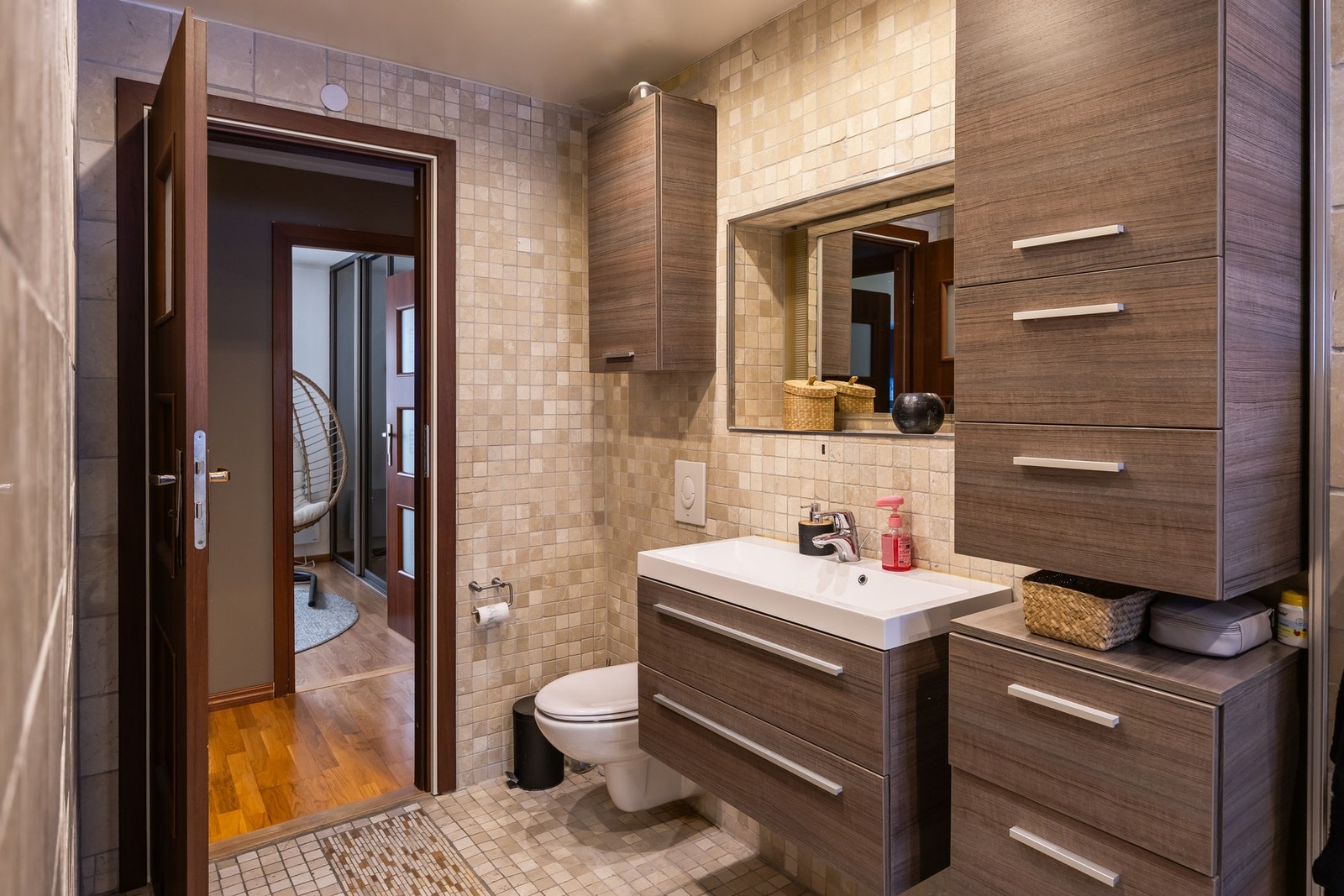 Bad med flislagte vegger og gulv, samt moderne baderomsinnredning i treverk. Galleribilde