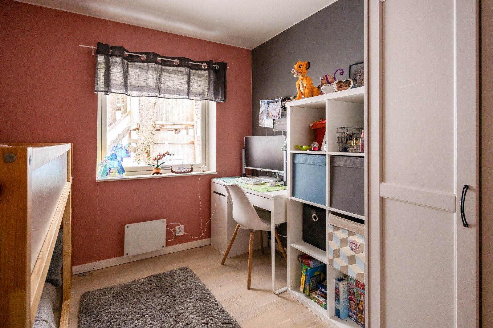 Rommet har vegger i to forskjellige farger, vindu med gardin, og innebygd oppbevaring. Galleribilde
