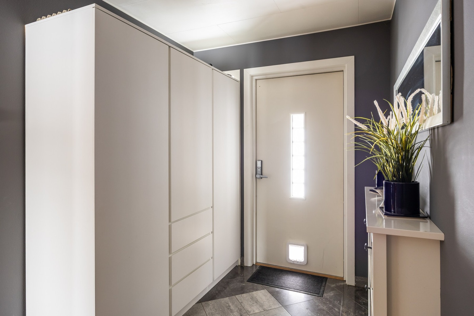 Lyst og funksjonelt inngangsparti med garderobeskap og flislagt gulv. Galleribilde