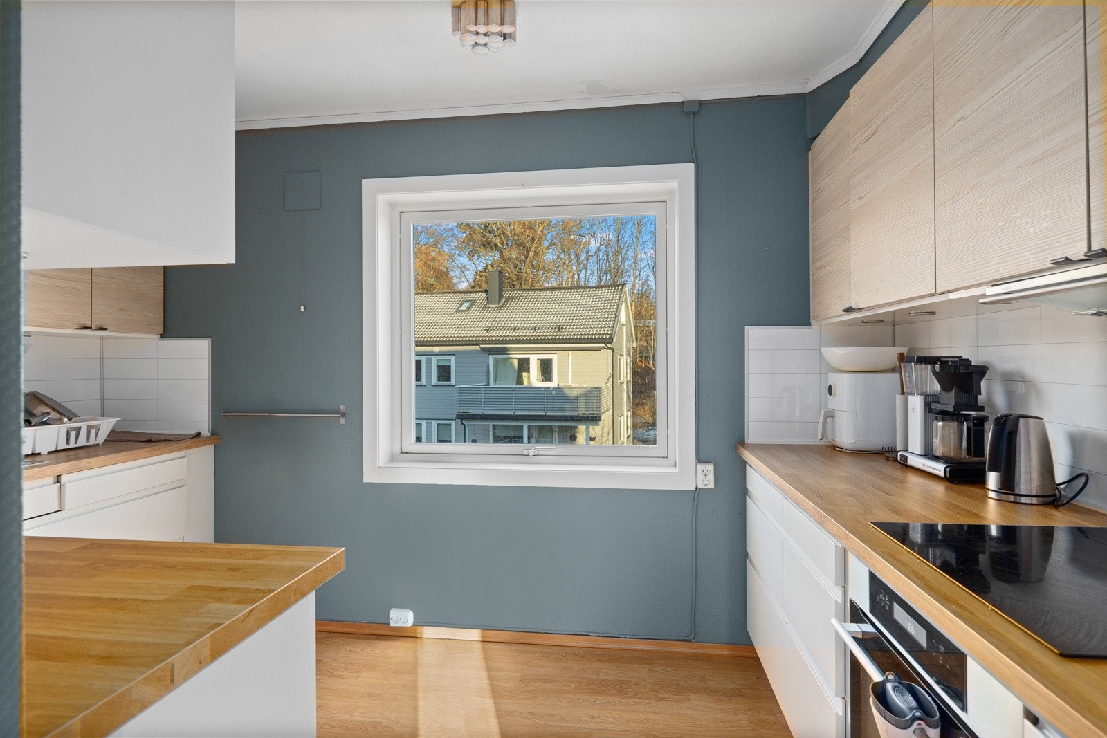 Pen kjøkkeninnredning med glatte fronter, benkeplater i laminat utførelse og benkebeslag med to kummer. Galleribilde