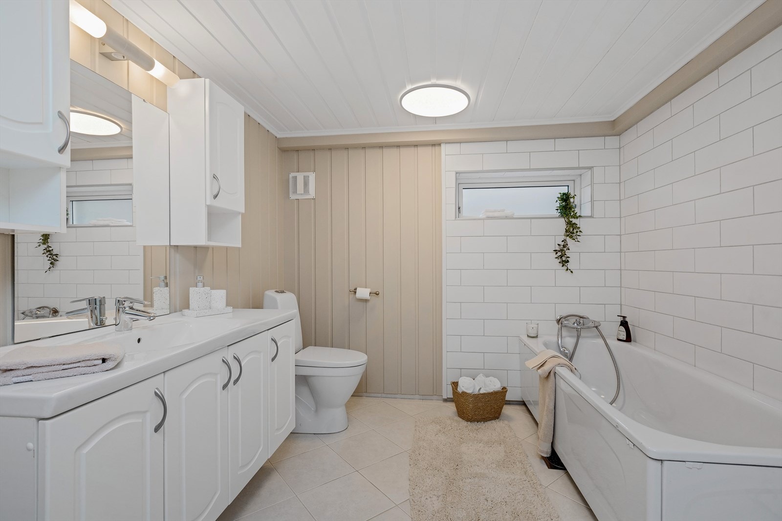 Bad i kjeller er fra ca. 2008. Innredet med en servantinnredning med skap og speil, et gulvmontert toalett og et badekar. Galleribilde