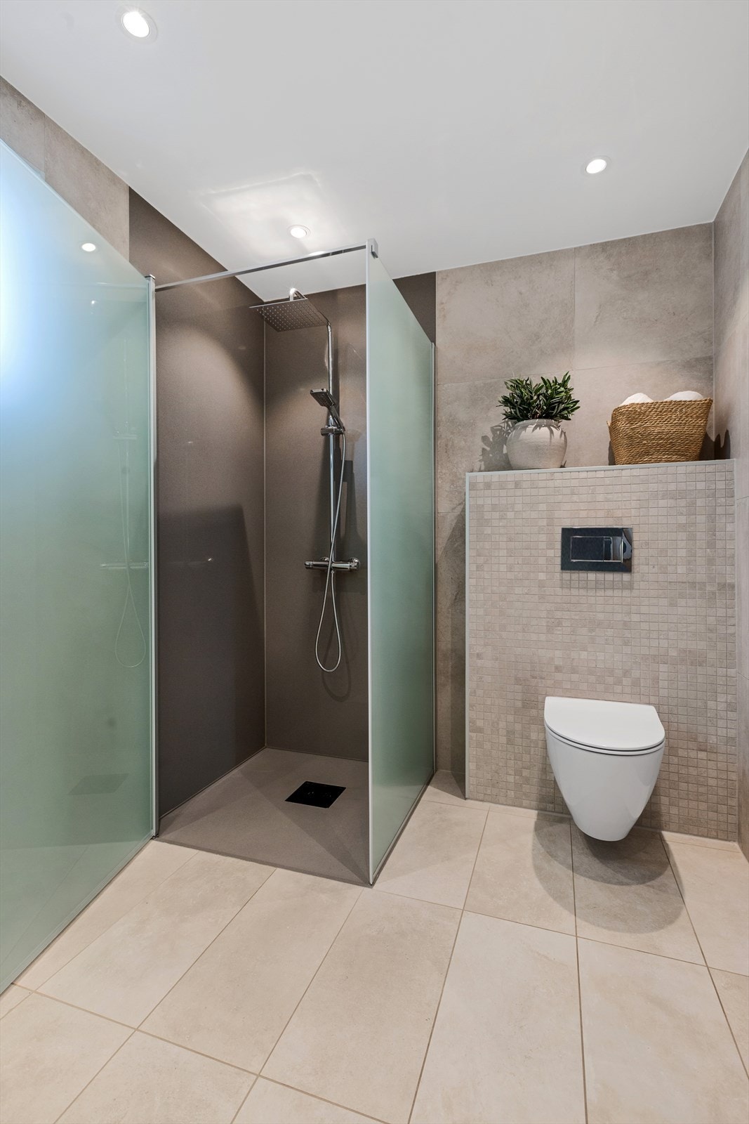 Innredningen består av en servantinnredning med skuffer og speilskap, et vegghengt toalett og en nedsenket dusj med glassdører. Galleribilde