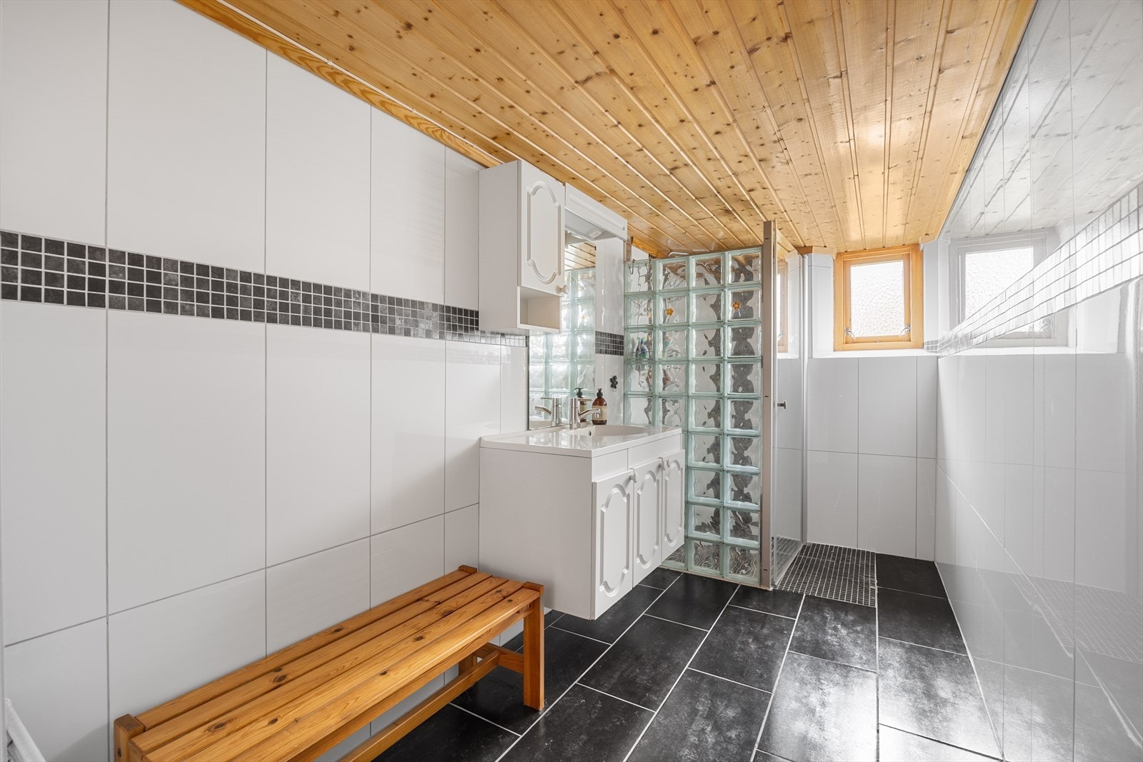 Hovedboligen har også bad i kjelleretasjen fra 2010 som er helfliset. Badet er av god størrelse, og er innredet med baderomsinnredning og dusjnisje. Galleribilde