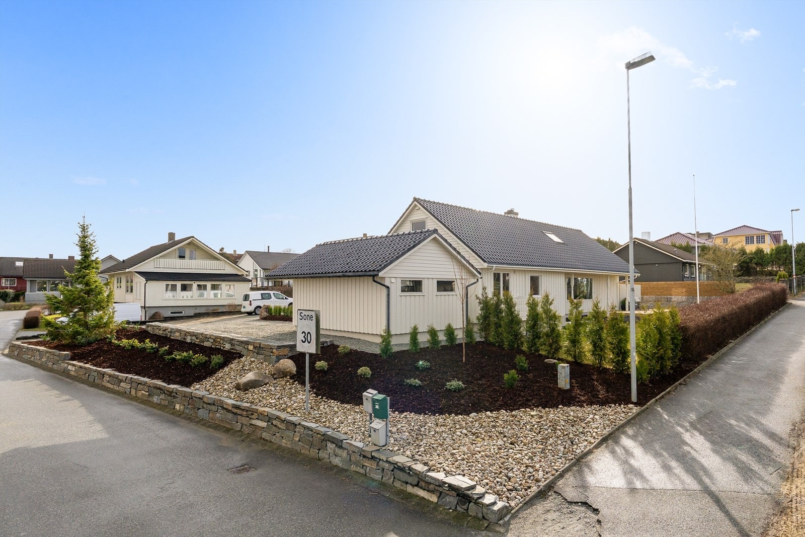 Eiendommen er pent opparbeidet med beplantning og stein Galleribilde