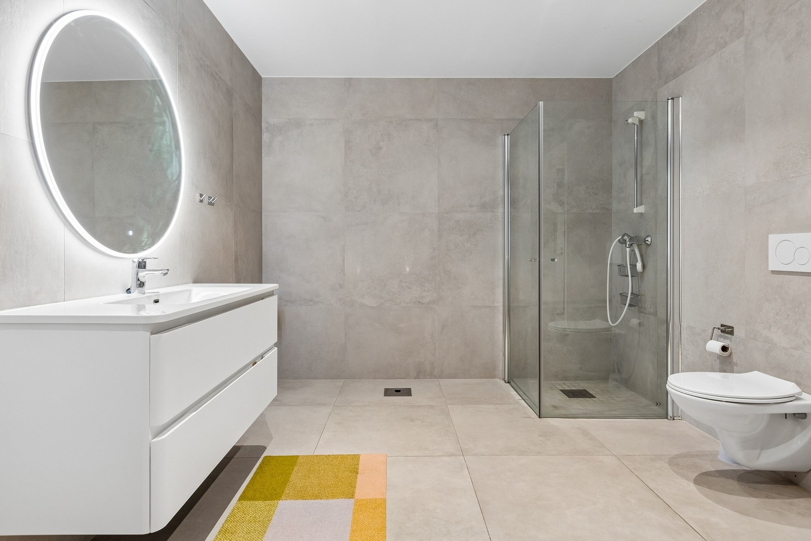 Lekkert bad med 60x60 fliser på gulv og vegg, vegghengt toalett og dusjnisje. Galleribilde