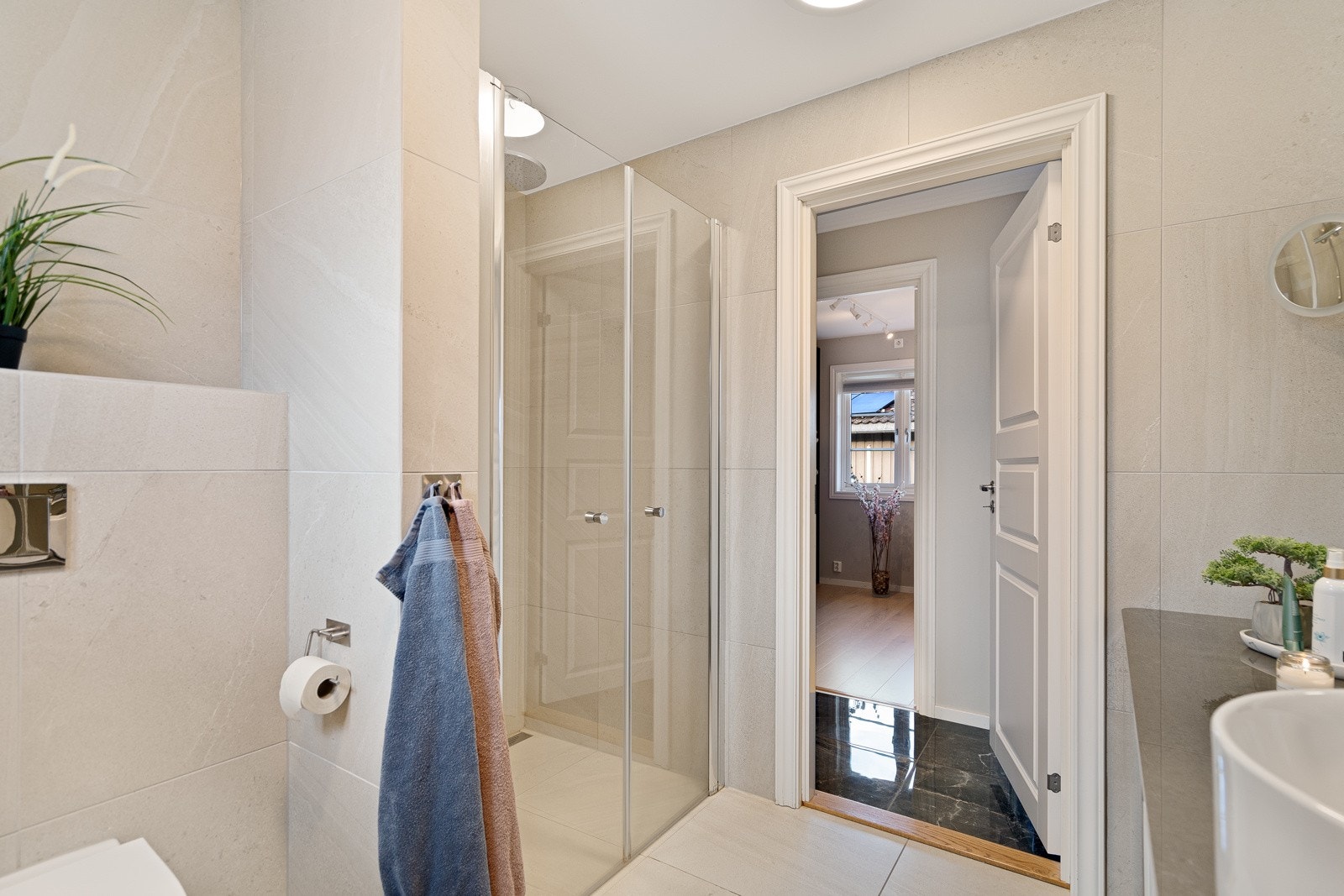 Begge badene har flislagte gulv med varmekabler og stilrene detaljer Galleribilde