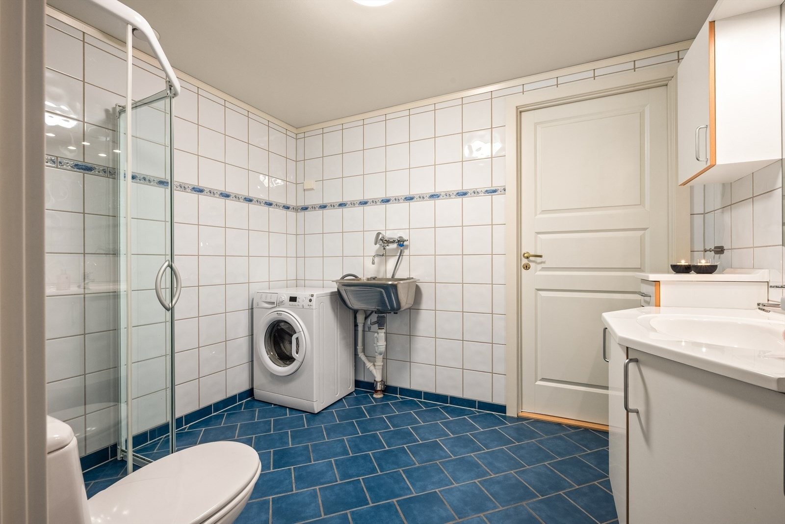 Rommet er et kombinert bad og vaskerom, med praktisk opplegg for vaskemaskin. Galleribilde