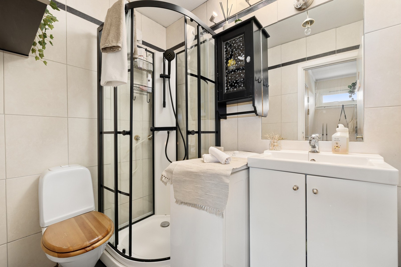 Pent flislagt bad som har servantskap med vask innebygd speil, veggskap og dusjkabinett. Det er opplegg til vaskemaskin og varmekabler i gulv. Galleribilde