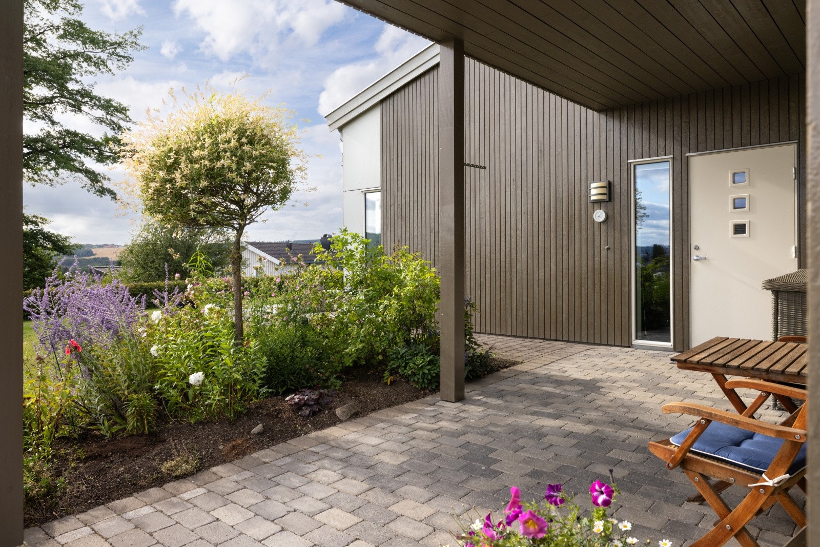 Inngangspartiet gir et svært godt førsteinntrykk. Det overbygde inngangspartiet, er pent opparbeidet med belegningsstein og et flott blomsterbed. Her gleder du deg til å komme hjem! Galleribilde