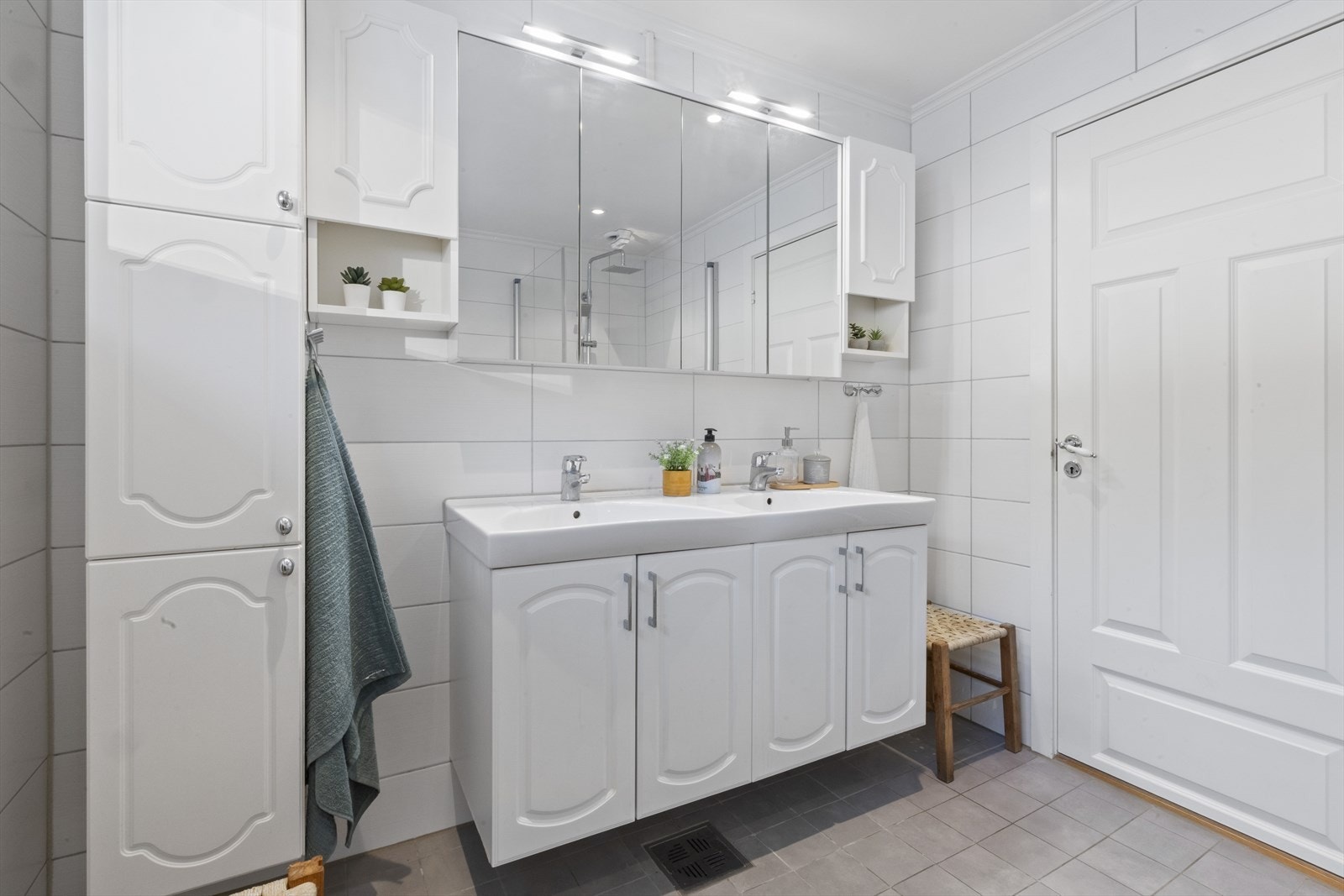 Flislagt tidsriktig baderom med lyse fliser og godt med oppbevaring Galleribilde