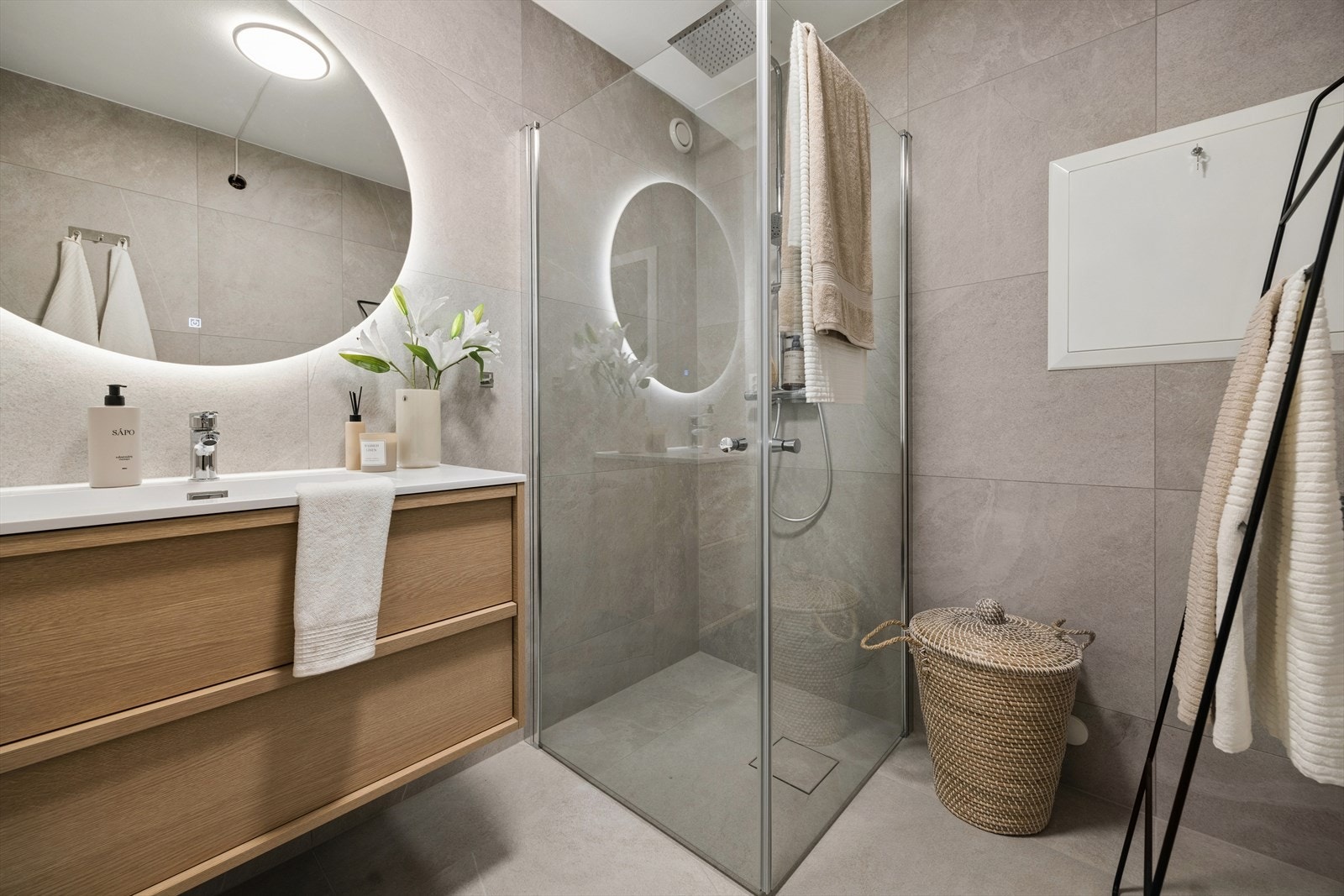 Flislagt bad med pen innredning og praktisk hjørnedusj med foldedører og takdusj. Her er det varme i gulv og det er benyttet en tidløs farge på flis. Galleribilde