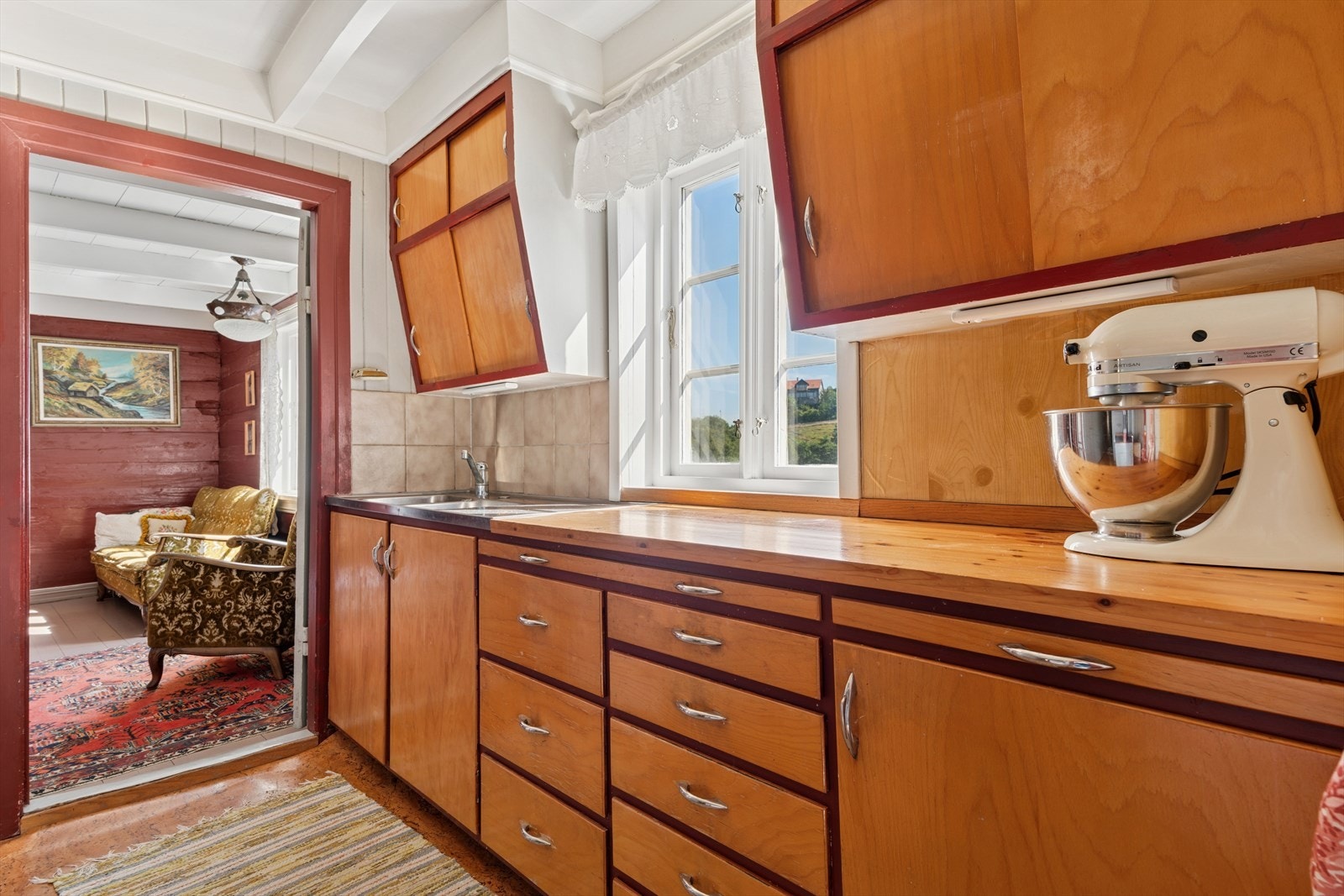 Kjøkkenet har en eldre innredning med glatte fronter og benkeplate i stål/tre. Galleribilde