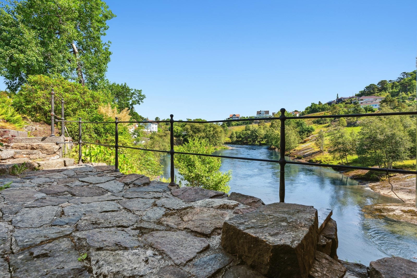 En uteplass i naturstein gir en privat sone helt nede ved elvebredden. Galleribilde