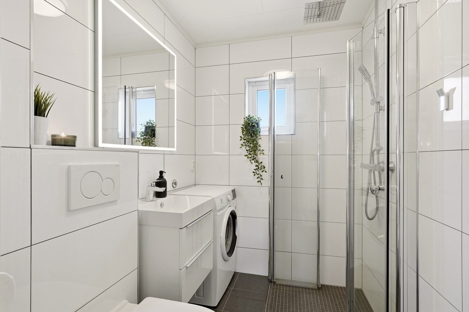 Fint bad med dusjhjørne, vegghengt toalett, opplegg til vaskemaskin og servant m/skuffer. Galleribilde