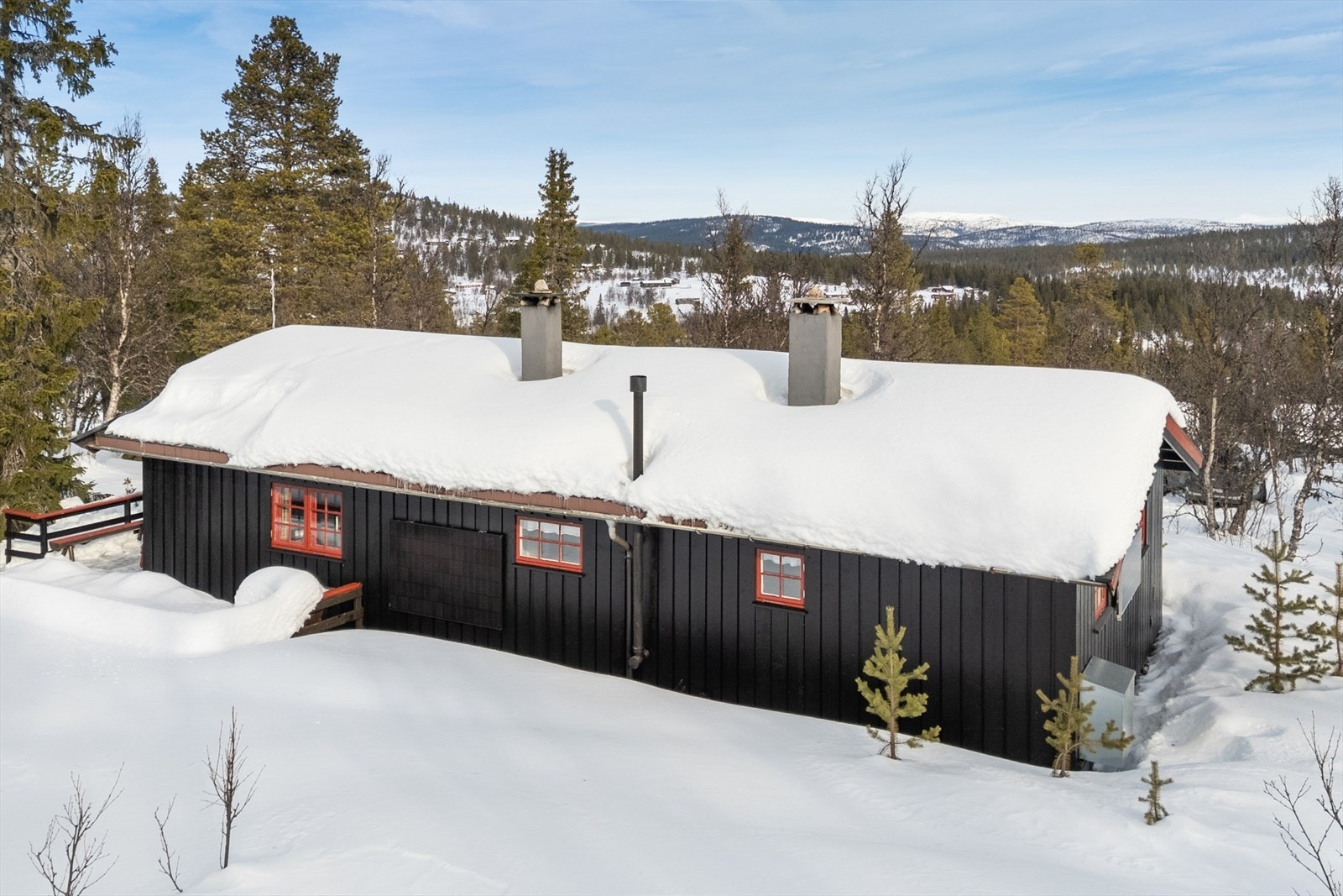 Hytta ligger fint til i landskapet med solcelleanlegg montert på vegg Galleribilde
