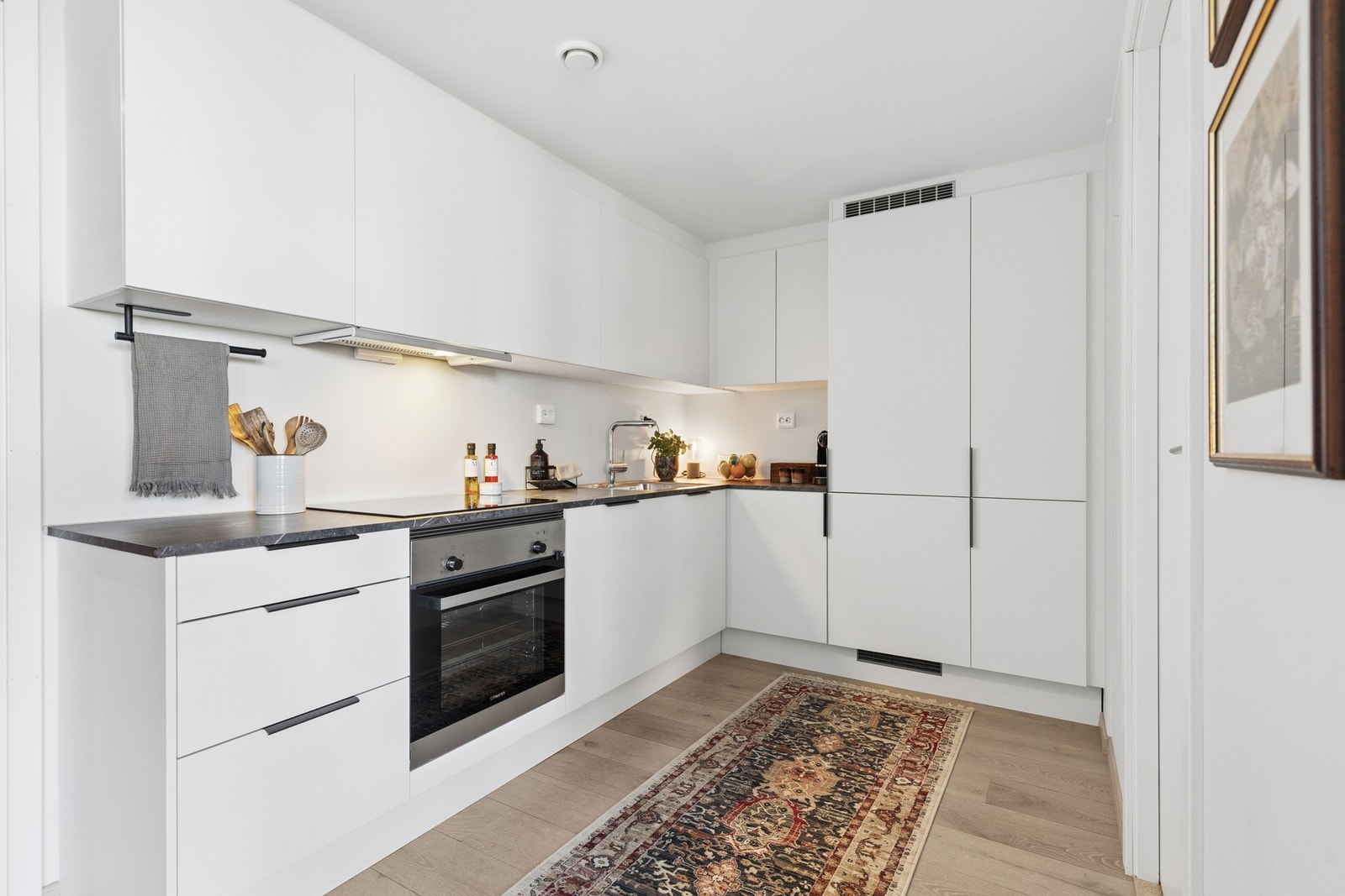 Kjøkkeninnredning med hvite fronter i glatt utførelse og laminat benkeplate. Galleribilde