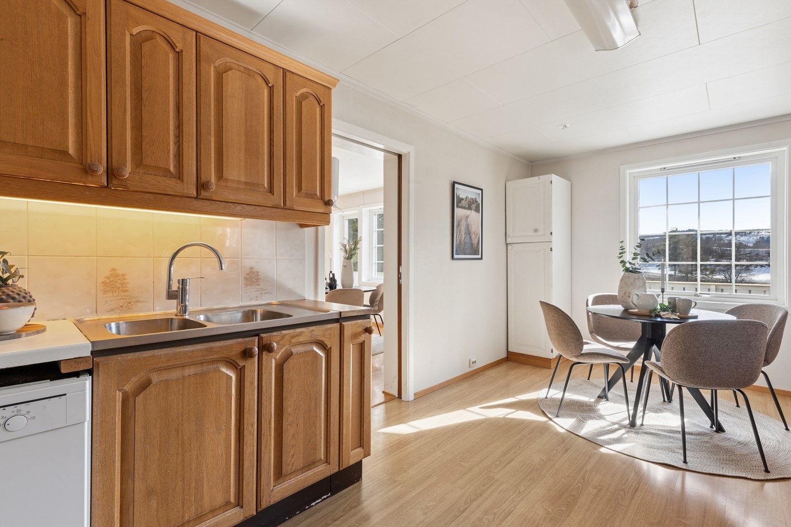 Kjøkkeninnredning med profilerte fronter og benkeplate i heltre og laminat med dobbel kjøkkenkum, flislagt over deler av benkeplate og belysning under overskap. Kjøkkenvifte med avtrekk ut. Galleribilde