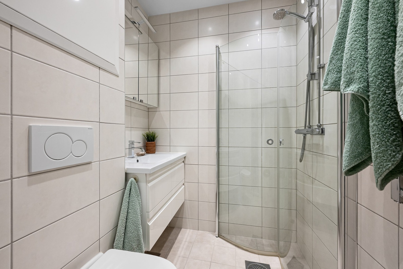 Baderom fra 2015 utstyrt med servantmøbel, dusjhjørne og WC med innebygget sisterne. Galleribilde