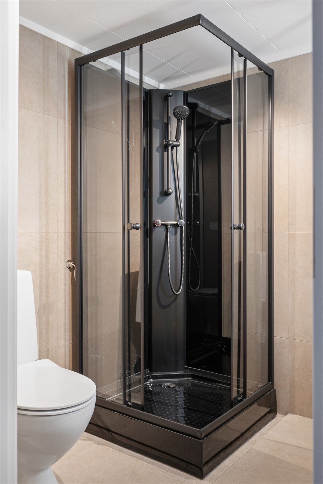 Praktisk dusjkabinett med sort omramming og glassdører. Galleribilde