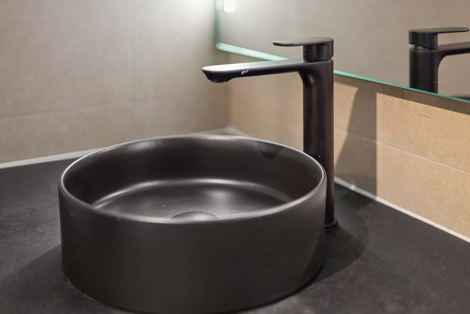 En stilren, sort keramisk servant med ettgrepsarmatur understreker det moderne uttrykket. Galleribilde