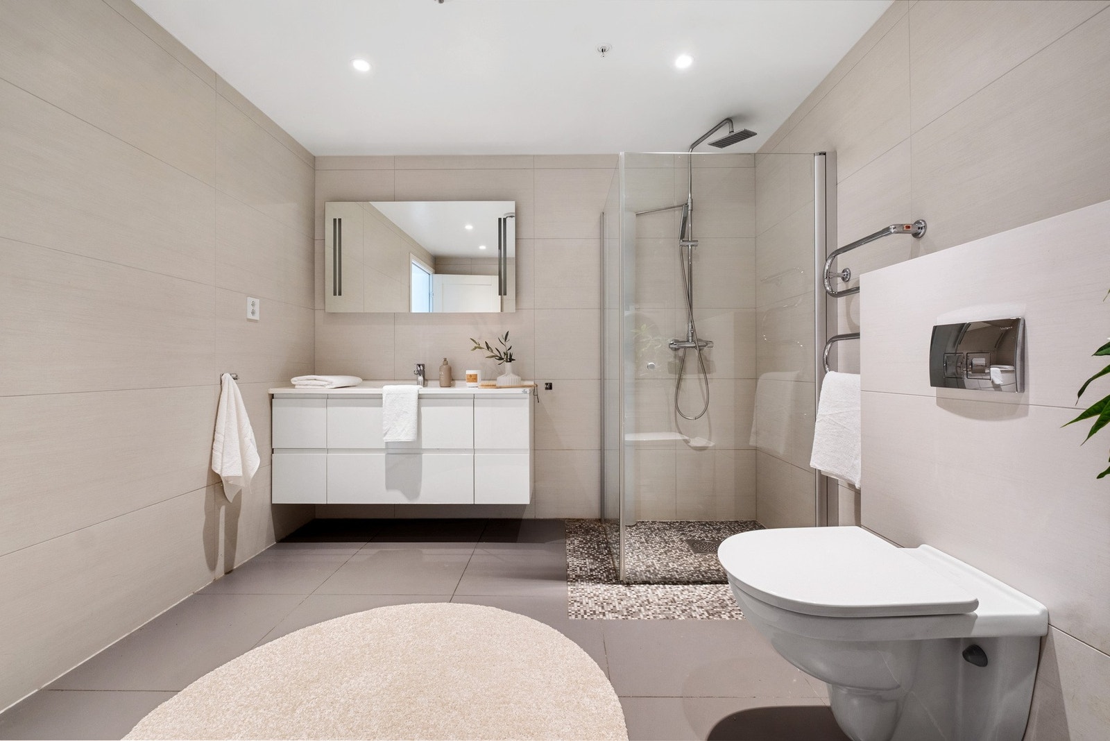 Rommet er innredet med nedfelt servant, veggmontert toalett, dusjvegger/hjørne og opplegg for vaskemaskin. Galleribilde