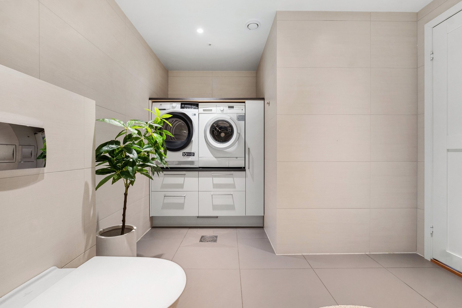 Praktisk vaskesone er etablert for vaskemaskin og tørketrommel med innredning med oppbevaringsplass. Galleribilde