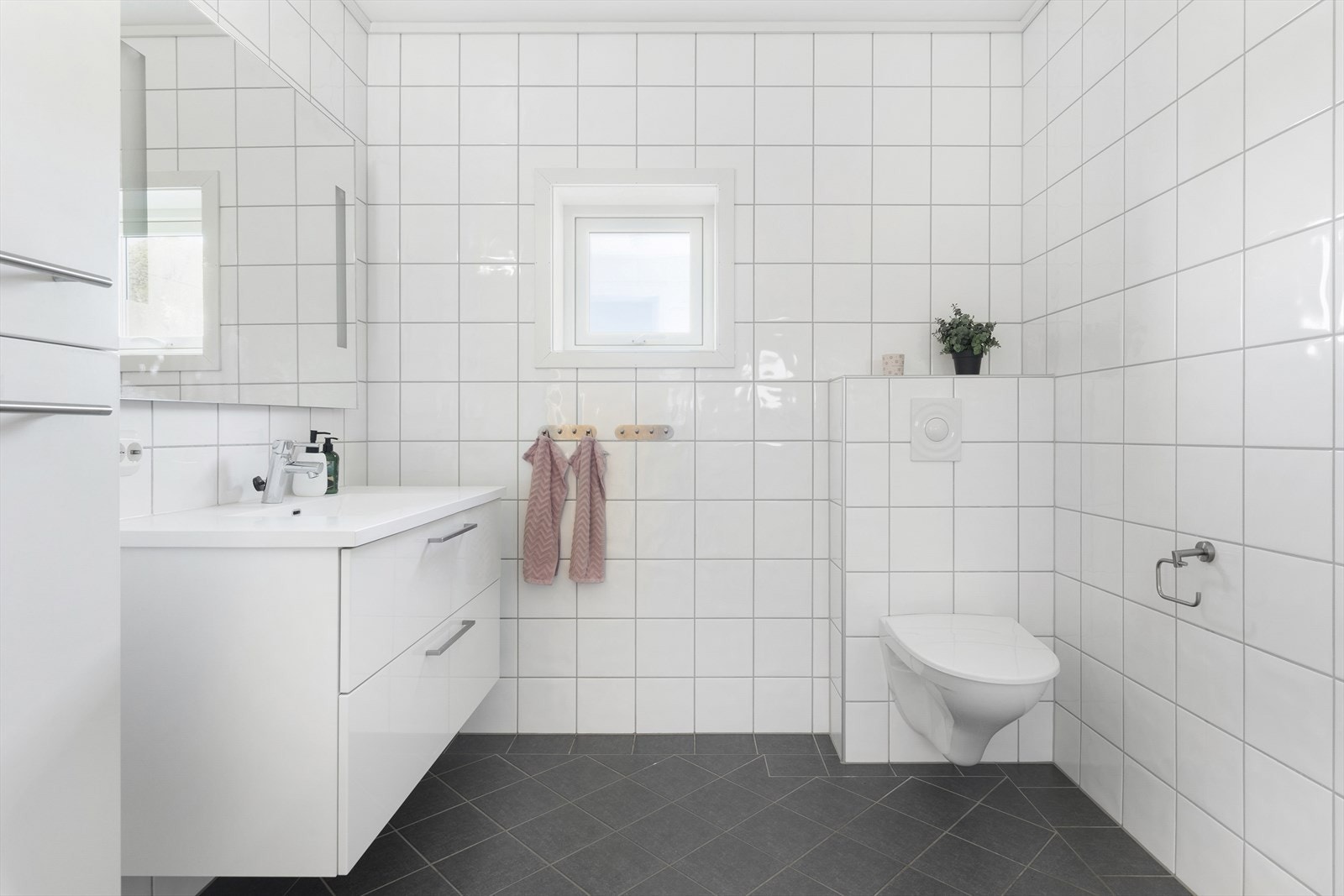Badet er lyst og tidløst, med fliser på gulv og vegger samt gulvvarme. Galleribilde