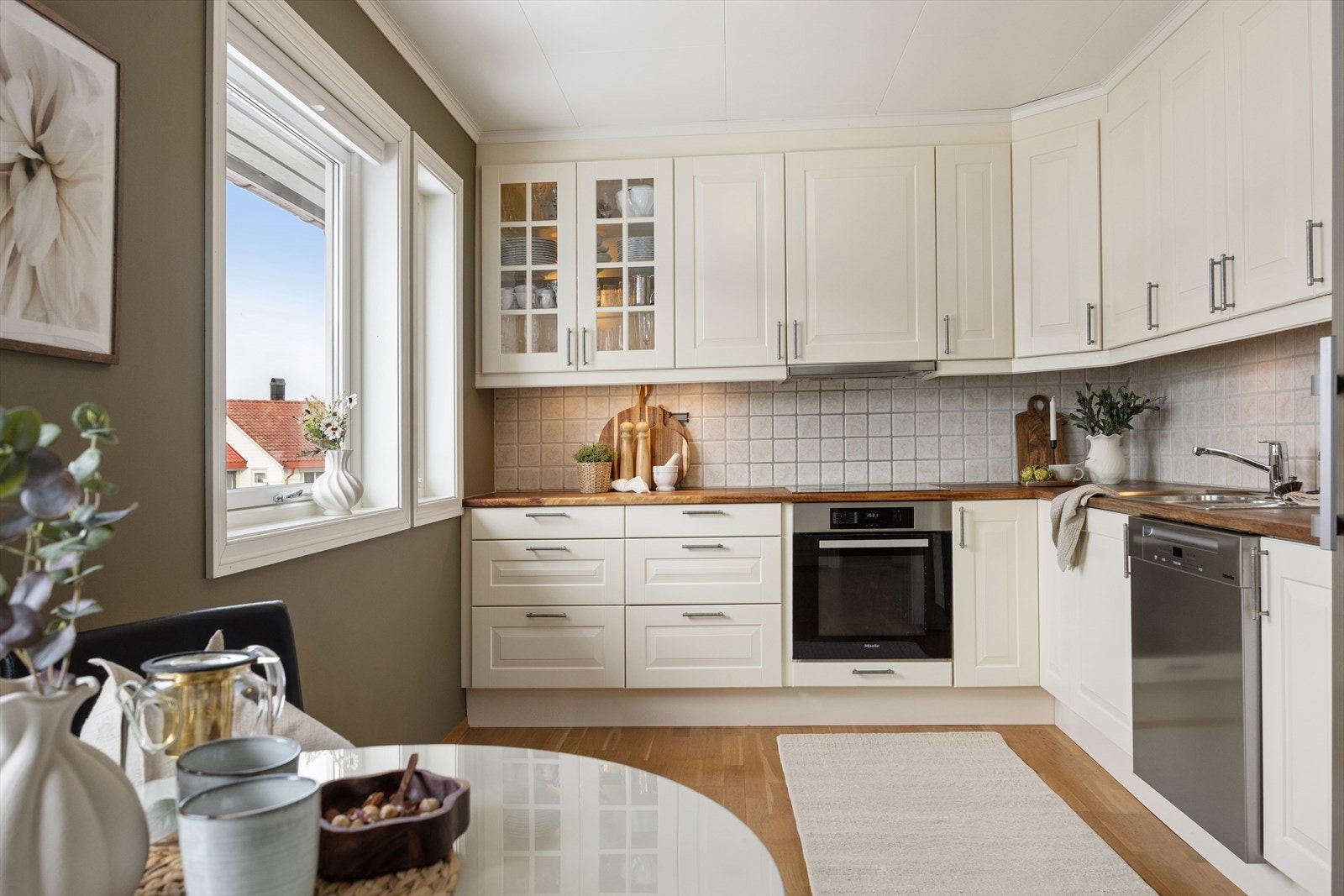 Lys og fin kjøkkeninnredning med profilerte fronter, benkeplate i heltre og integrerte hvitevarer. Galleribilde