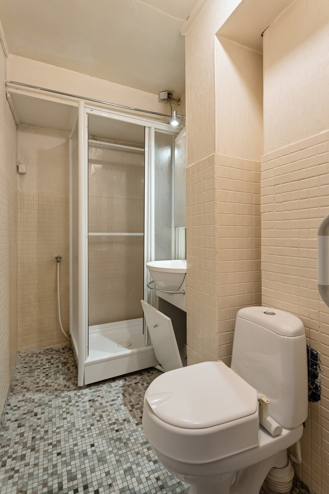 Badet ble etablert i 1968 og har flislagt gulv, malt flisbrystning og malt tapet på vegger. Innredningen inkluderer en heldekkende servant, toalett, dusjkabinett og opplegg for vaskemaskin, supplert med et speilskap med lys. Galleribilde