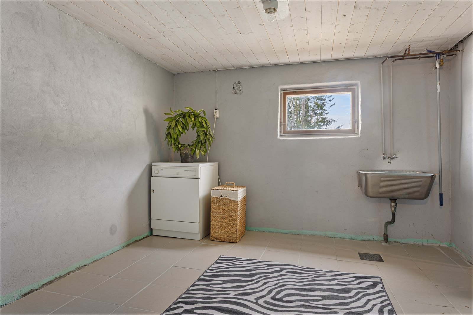 Praktisk vaskerom med opplegg for vaskemaskin og god plass til håndtering av klesvask. Galleribilde