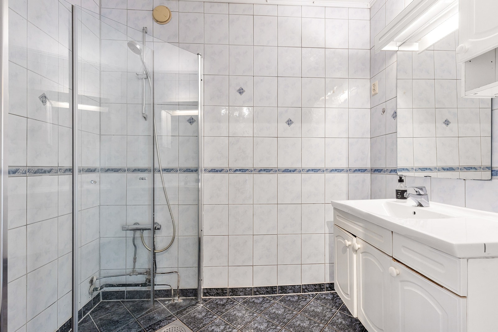 Badet er helfliset og utstyrt med elektrisk gulvvarme og et dusjhjørne med svingbare glassdører. Galleribilde