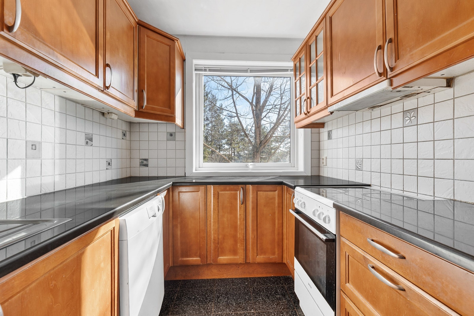 Kjøkkenet har en solid innredning med profilerte fronter og benkeplate i stein. Galleribilde