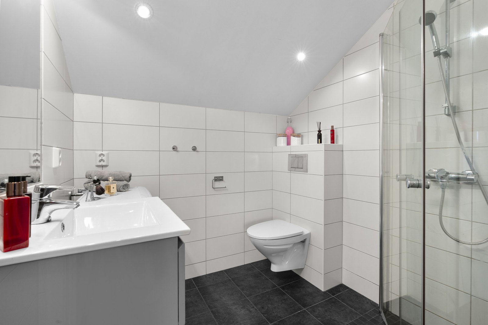 Leiligheten har et lyst flislagt baderom fra 2014. Baderommet har mørke fliser på gulv, elektrisk gulvvarme, hvite fliser på veggene, downlights i himlingen og mekanisk avtrekksvifte. Galleribilde