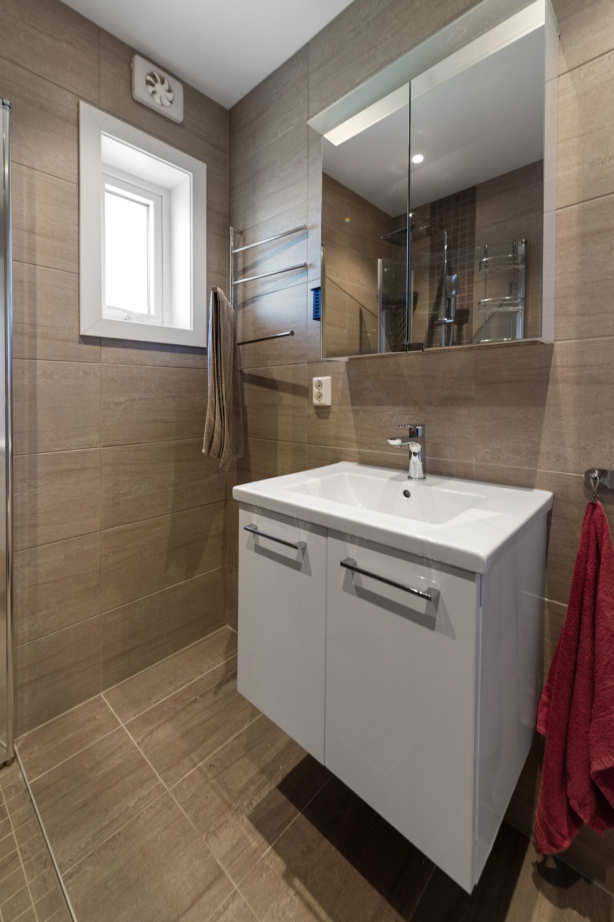 Badet har gulvvarme og er utstyrt med dusjhjørne med glassdører, servant med underskap, samt vegghengt toalett. Galleribilde