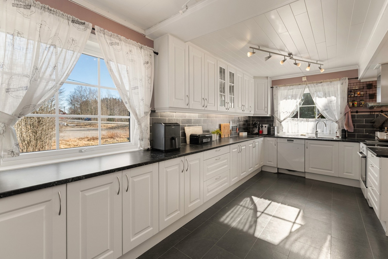 Romslig og lyst kjøkken med store vindusflater som slipper inn rikelig med naturlig lys, samt generøst med benkeplass til matlaging, baking og sosiale sammenkomster. Galleribilde