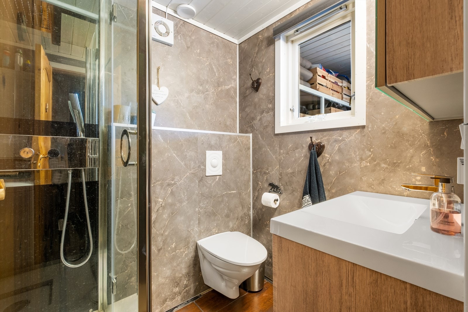 Badet har baderomsplater på veggene, vegghengt toalett og dusjkabinett. Galleribilde