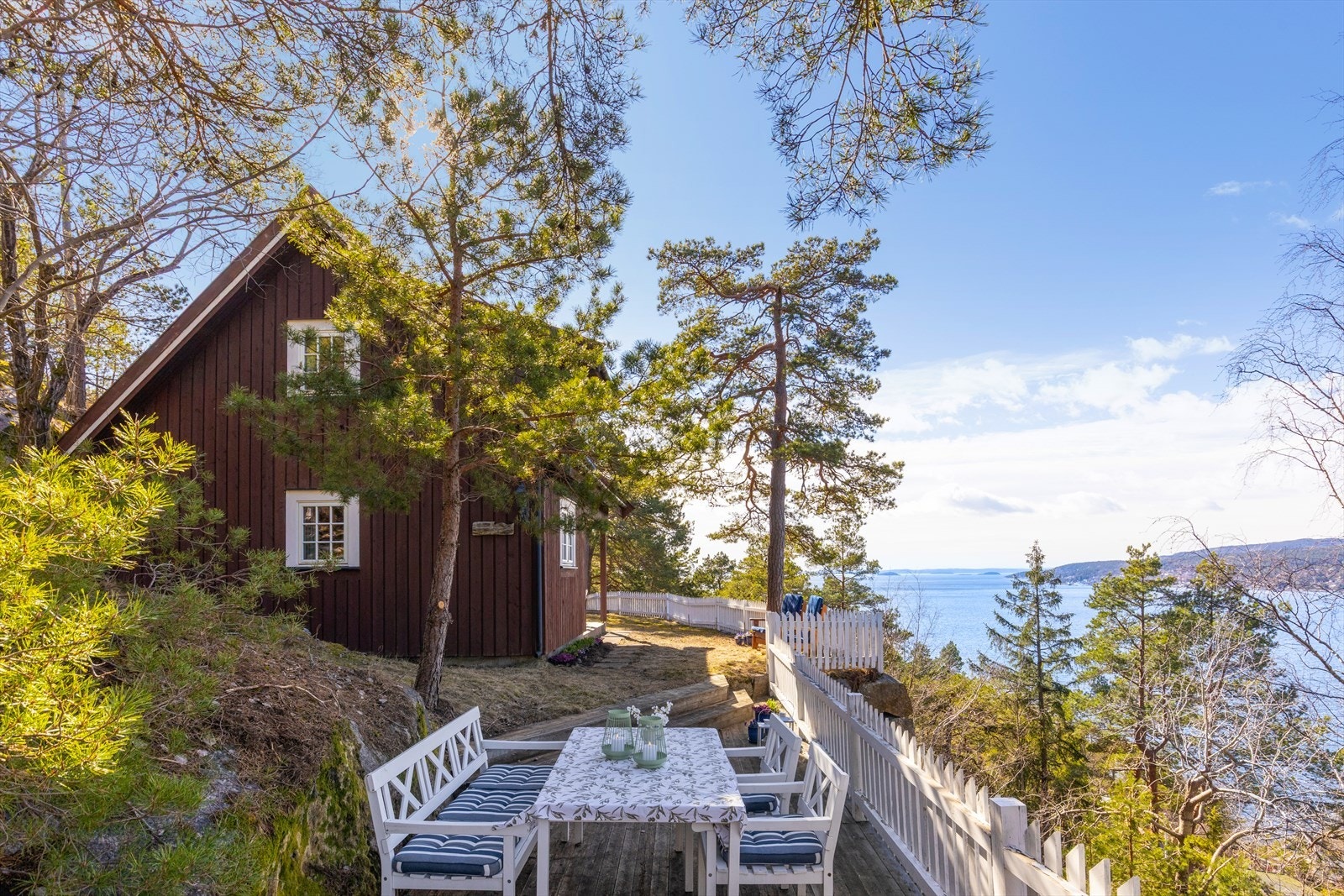 Den lune plasseringen mellom trærne gir en fin kombinasjon av skjerming og åpen utsikt, og skaper en helt egen hytteidyll ved kysten. Galleribilde