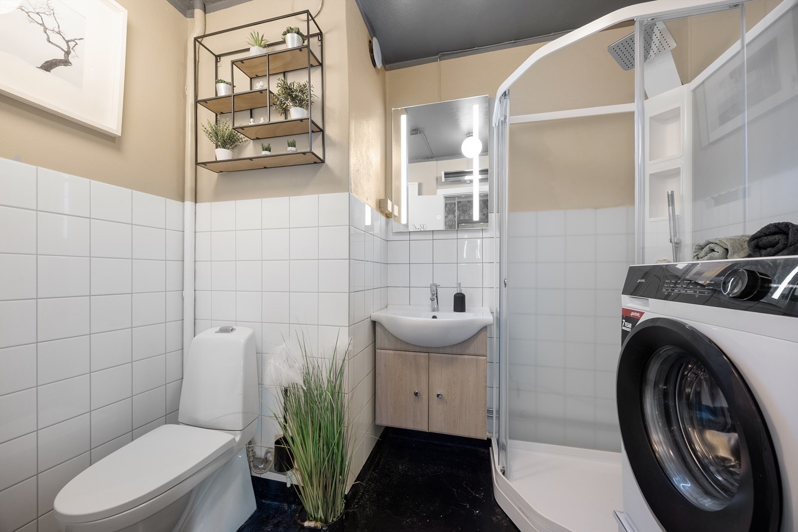 Badet er innredet med toalett, dusjkabinett, servantinnredning og opplegg for vaskemaskin. Galleribilde