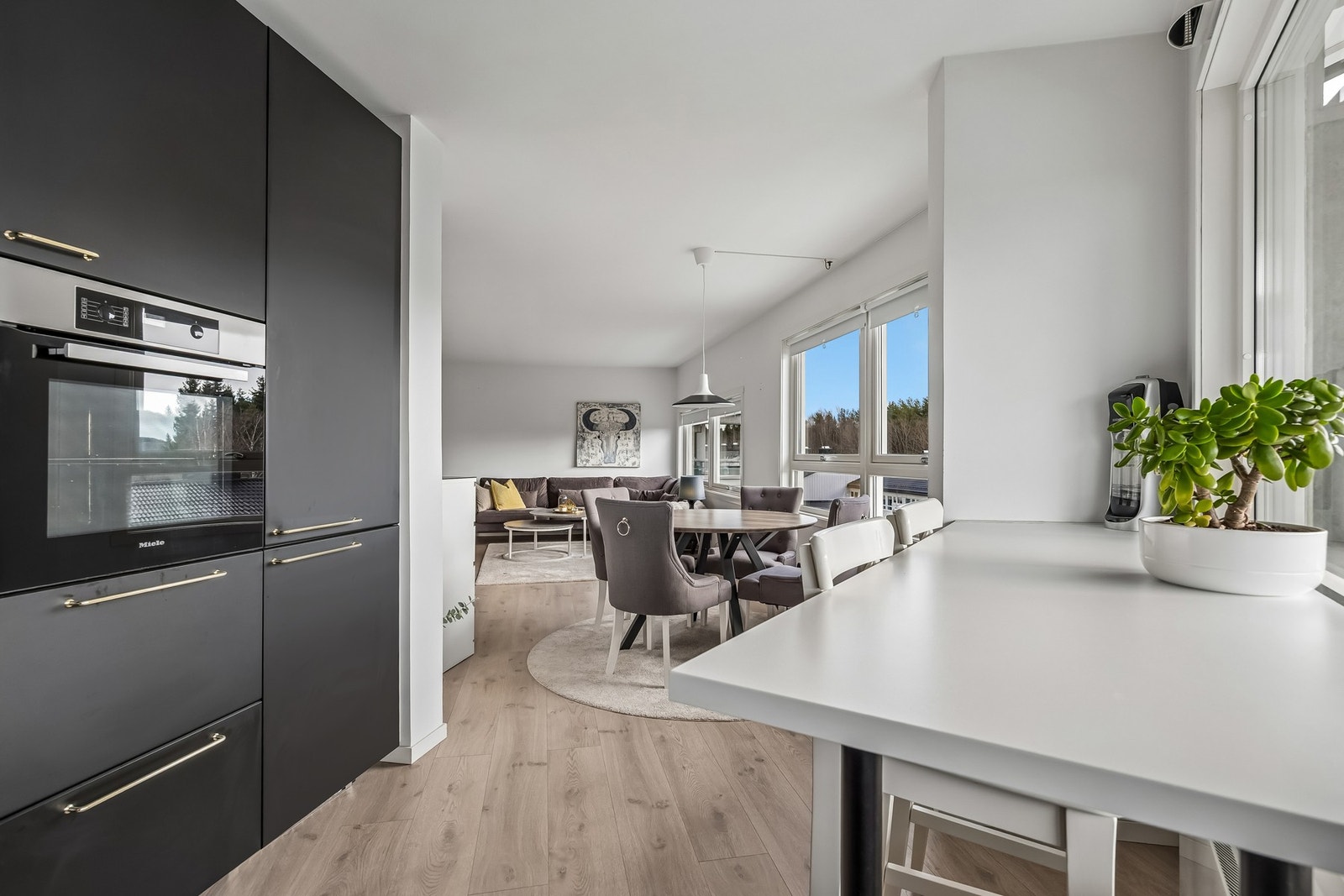 Plasseringen tett på kjøkkenet gjør servering og matlaging effektivt og praktisk, samtidig som det gir en naturlig inndeling av rommet uten at det føles oppdelt. Galleribilde