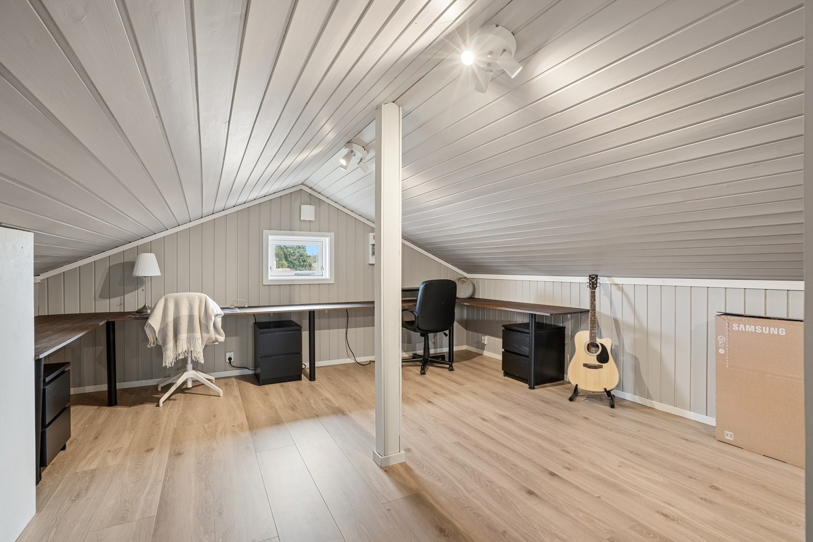 Loftet er innredet til en ekstra stue, med laminat på gulvene og plater på veggene Galleribilde