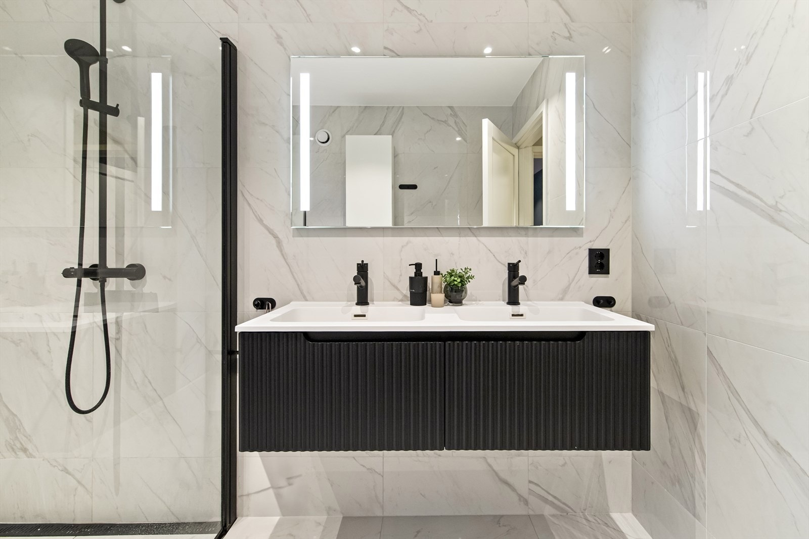 De mørke detaljene på armaturer og dusjvegger gir rommet et moderne preg. Galleribilde